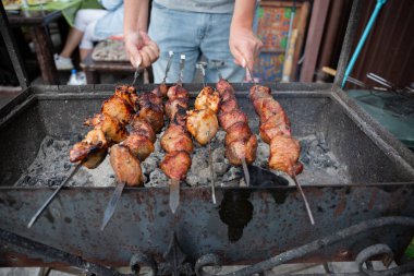 Adam bir yaz günü özel bir evin arka bahçesinde ateşte et kebabı pişiriyor..