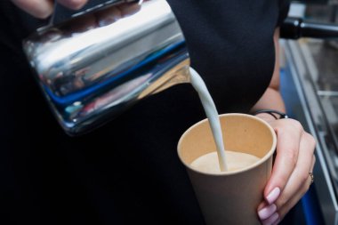 Barista kahve dükkanında sütlü kapuçino hazırlıyor.