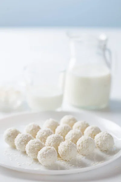 Dessert coconut cake and milk in a jug on a light background