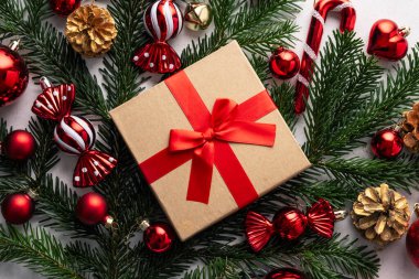 Noel hediyesi kutusu, köknar dalları ve beyaz arka planda kırmızı süsler. Fotokopi alanı olan bayram dairesi.