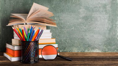 Okul kitaplarına geri dön. Kalem tutucu ve büyüteçleri masa tahtası arka planına istifle.