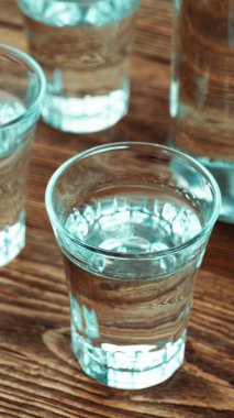 Dikey votka şişesi ve kadehler ahşap masa hikâyesi formatı