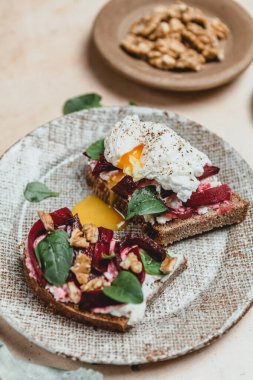 Fırında pancar, haşlanmış yumurta, tabakta fındık ve şifalı otla birlikte bruschetta, sağlıklı bir kahvaltı konsepti.