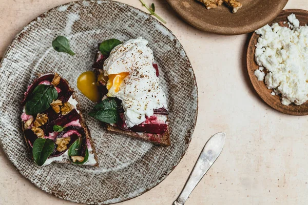 Fırında pancar, haşlanmış yumurta, tabakta fındık ve şifalı otla birlikte bruschetta, sağlıklı bir kahvaltı konsepti.