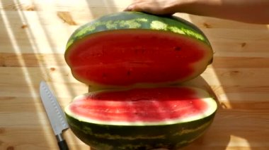 Karpuzu bıçakla kes. Büyük olgun kırmızı meyve. Yazın doğadan vitaminler