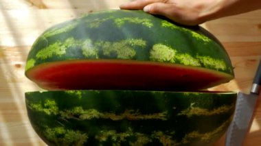 Karpuzu bıçakla kes. Büyük olgun kırmızı meyve. Yazın doğadan vitaminler