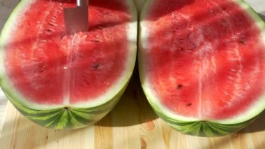 Karpuzu bıçakla kes. Büyük olgun kırmızı meyve. Yazın doğadan vitaminler