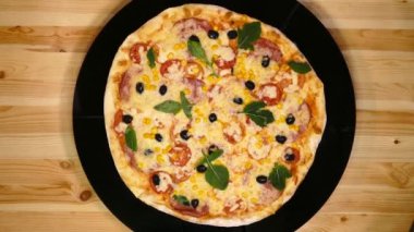 Pizzaya yakın çekim. Ürünlerin teslimatı. Peynirli pizza, domates ve zeytinli.