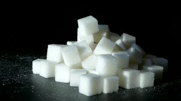 Açúcar refinado close-up em um fundo preto. Ingrediente doce. Alimentação saudável e diabetes. — Vídeo de Stock
