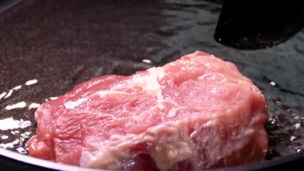 Un morceau de viande crue est frit dans l'huile. Faire cuire le steak de porc dans une casserole. Préparer le déjeuner dans la cuisine. — Video
