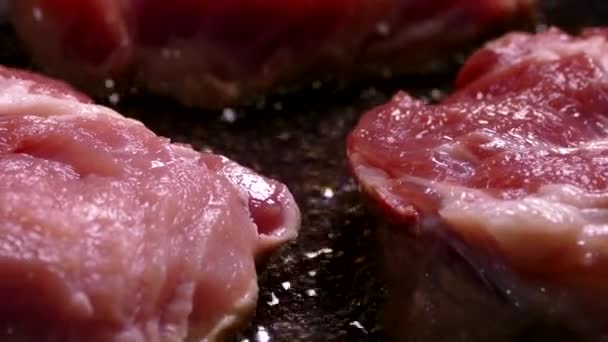 Een stuk rauw vlees wordt gebakken in olie. Kook varkensvlees in een pan. Maak de lunch klaar in de keuken. — Stockvideo