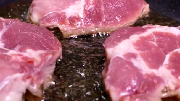 Um pedaço de carne crua é frito em óleo. Cozinhe o bife de porco em uma panela. Prepare o almoço na cozinha. — Vídeo de Stock