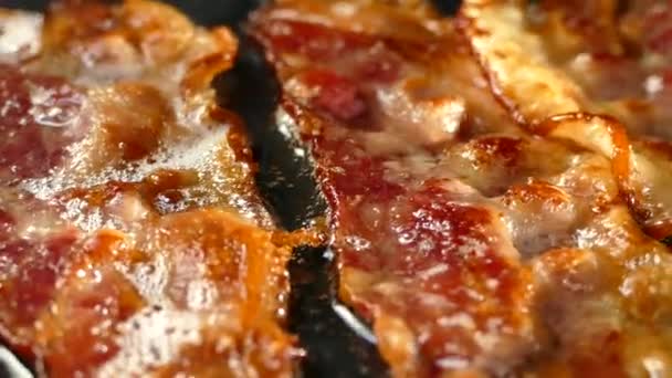 프라이팬에 베이컨튀기기. 돼지고기 베이컨 한 조각은 그 자체의 지방으로 만들어 집니다. 고기와 돼지고기를 먹는 사람. 부엌에 있는 모습. — 비디오