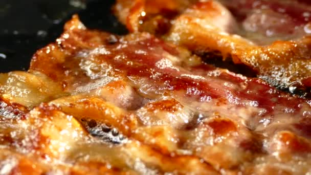 Fry the bacon in a pan. A slice of pork bacon is prepared in its own fat. Layer of meat and lard. Close up in the kitchen. — Stock Video