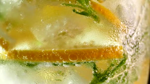 ソフトドリンクをアイスでさっぱり レモンとミントをグラスに入れたモヒート 炭酸水を閉じ込めます ガラスに冷たい露の滴 — ストック動画