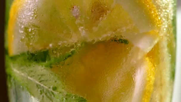 Boisson rafraîchissante avec glace. Mojito au citron et menthe dans un verre. Eau carbonatée à proximité. Des gouttes de rosée froide sur un verre. — Video