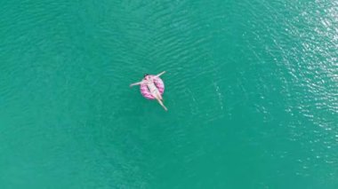 Şişme dairedeki kız suyun üzerinde yüzüyor. Denizde dinlenme ve rahatlama. Okyanusta dinlenen bir kadının manzarası..