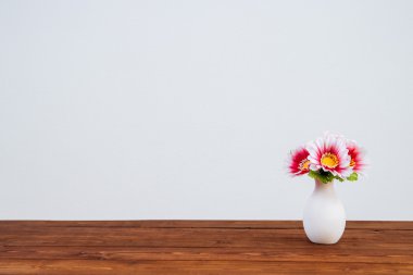 Ahşap masa ve beyaz duvar çiçek