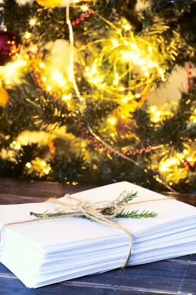 Letter to Santa Claus. Christmas background with a stack of envelopes, xmas tree , pine branches, lights and Golden sparkles light. light blur