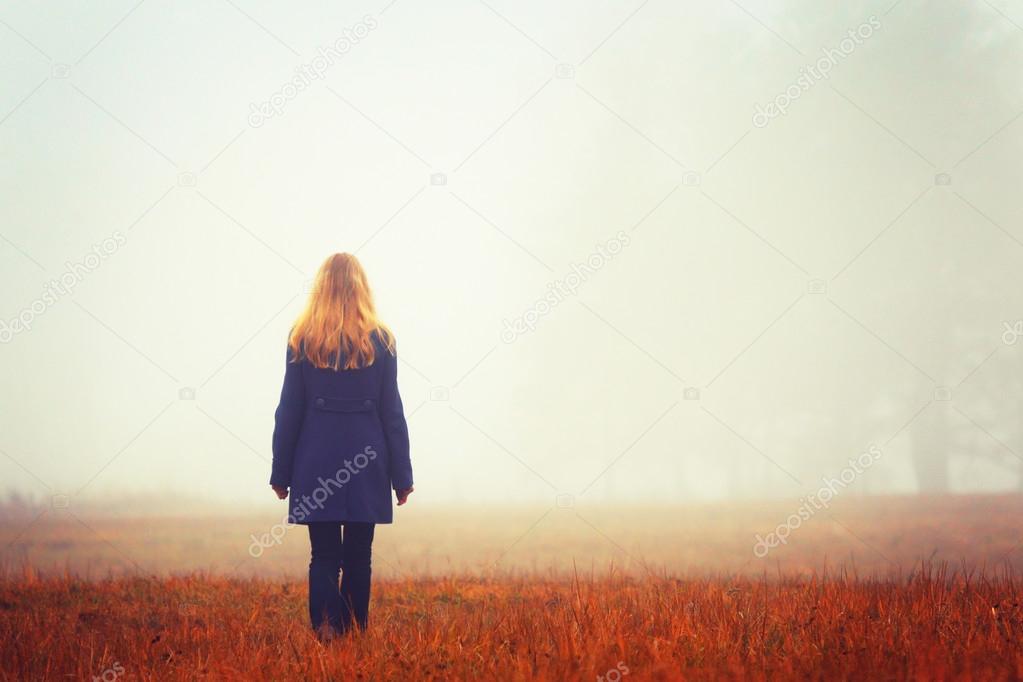 Blonde woman on walk.Autumn wood. Fog background. Quiet landscap