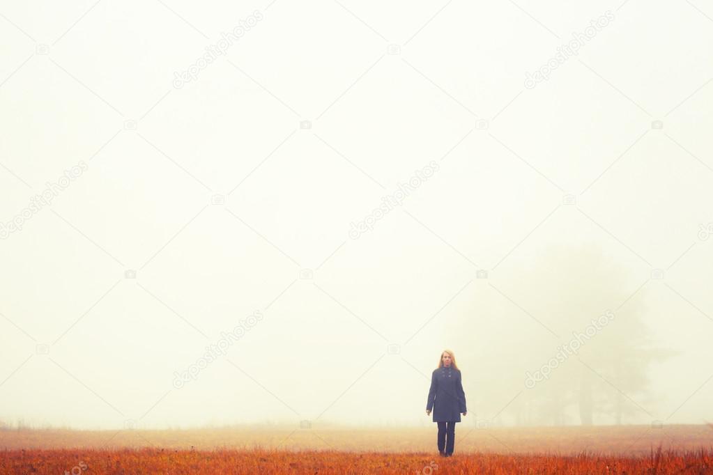 Blonde woman on walk.Autumn wood. Fog background. Quiet landscap