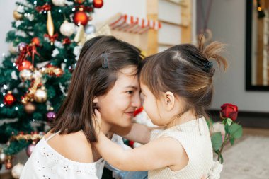 Noel ağacının yanında oturan hediyeli iki kız kardeş