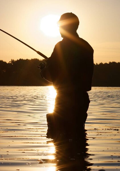 Силуэт рыбака в лучах восходящего солнца