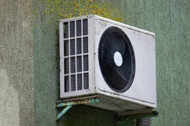 Binanın dışındaki havalandırma yoğunlaştırıcı ünitesi ve duvardaki yeşil mantar.