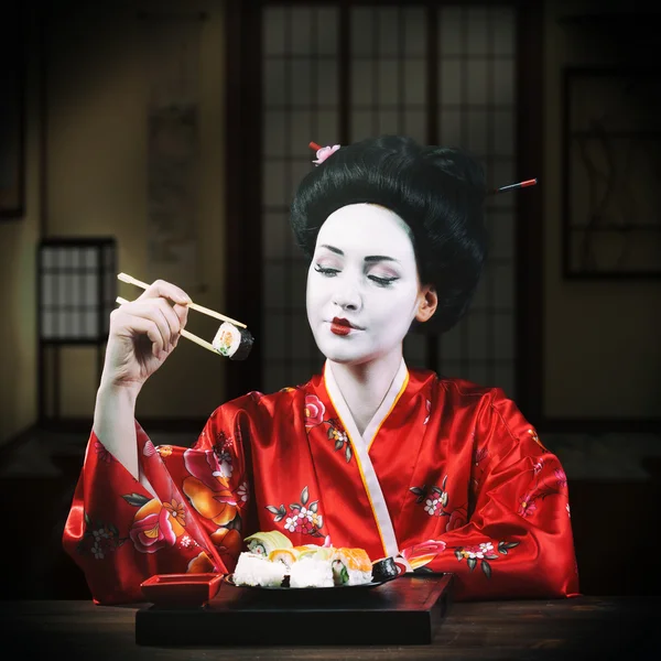 Woman in geisha makeup eating sushi — Stock Photo, Image