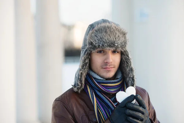 Young man with a heart shaped snowball — Stock Photo, Image