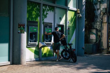 Tel Aviv İsrail 2 Kasım 2020 Coronavirus salgını sırasında Tel Aviv 'in boş sokaklarındaki ATM' yi kullanarak kendini virüsten korumak için yüzü maskeli kimliği belirsiz insanların görüntüsü.