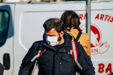 Fransa 'yı 14 Kasım 2020' de Coronavirus salgını sırasında ve nüfusu kontrol altına almak için çarşıda maske alışverişi yapan kimliği belirsiz kişilerin portresi olarak gösteriyor.