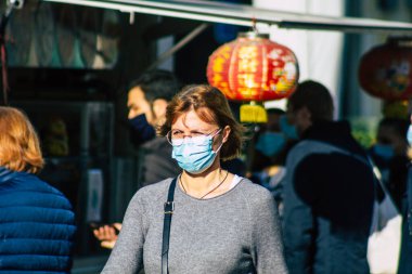 Fransa 'yı 14 Kasım 2020' de Coronavirus salgını sırasında ve nüfusu kontrol altına almak için çarşıda maske alışverişi yapan kimliği belirsiz kişilerin portresi olarak gösteriyor.