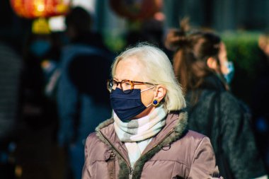 Fransa 'yı 14 Kasım 2020' de Coronavirus salgını sırasında ve nüfusu kontrol altına almak için çarşıda maske alışverişi yapan kimliği belirsiz kişilerin portresi olarak gösteriyor.