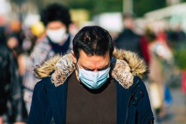 Fransa 'yı 14 Kasım 2020' de Coronavirus salgını sırasında ve nüfusu kontrol altına almak için çarşıda maske alışverişi yapan kimliği belirsiz kişilerin portresi olarak gösteriyor.