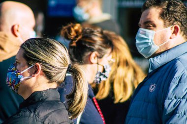 Fransa 'yı 14 Kasım 2020' de Coronavirus salgını sırasında ve nüfusu kontrol altına almak için çarşıda maske alışverişi yapan kimliği belirsiz kişilerin portresi olarak gösteriyor.