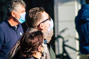 Fransa 'yı 14 Kasım 2020' de Coronavirus salgını sırasında ve nüfusu kontrol altına almak için çarşıda maske alışverişi yapan kimliği belirsiz kişilerin portresi olarak gösteriyor.