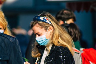 Fransa 'yı 14 Kasım 2020' de Coronavirus salgını sırasında ve nüfusu kontrol altına almak için çarşıda maske alışverişi yapan kimliği belirsiz kişilerin portresi olarak gösteriyor.