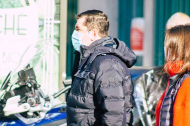 Fransa 'yı 14 Kasım 2020' de Coronavirus salgını sırasında ve nüfusu kontrol altına almak için çarşıda maske alışverişi yapan kimliği belirsiz kişilerin portresi olarak gösteriyor.