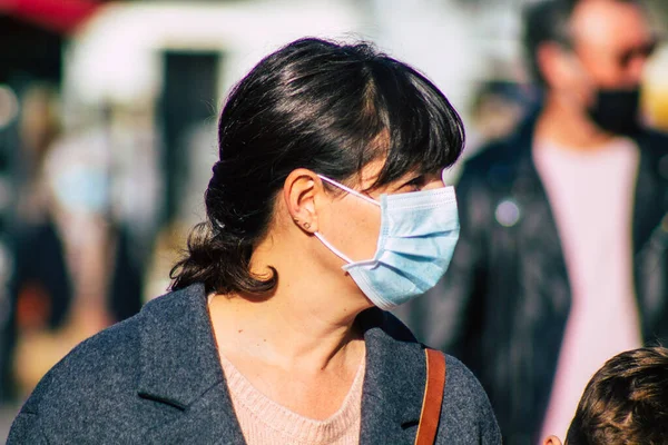 Fransa 'yı 14 Kasım 2020' de Coronavirus salgını sırasında ve nüfusu kontrol altına almak için çarşıda maske alışverişi yapan kimliği belirsiz kişilerin portresi olarak gösteriyor.