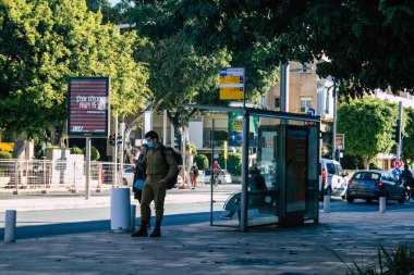 Tel Aviv İsrail 28 Aralık 2020 'de İsrail' deki Coronavirus salgını sırasında otobüs durağında bekleyen yüzü maskeli kimliği belirsiz bir İsrailli 'nin görüntüsü.