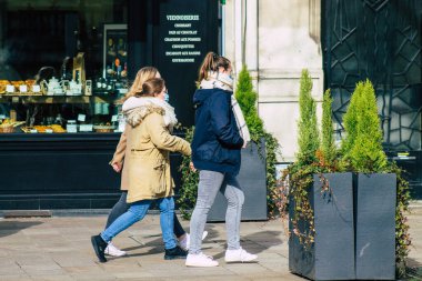 Fransa 'yı 16 Şubat 2021' de Reims sokaklarında yürüyen ve Fransa 'yı etkileyen salgın sırasında kendilerini koronavirüsten korumak için maske takan kimliği belirsiz bir yaya.