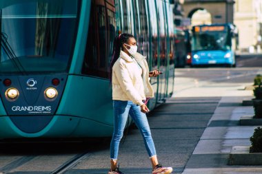 Fransa 'yı 16 Şubat 2021' de Reims sokaklarında yürüyen ve Fransa 'yı etkileyen salgın sırasında kendilerini koronavirüsten korumak için maske takan kimliği belirsiz bir yaya.