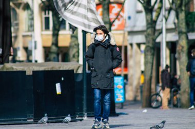 Fransa 'yı 16 Şubat 2021' de Reims sokaklarında yürüyen ve Fransa 'yı etkileyen salgın sırasında kendilerini koronavirüsten korumak için maske takan kimliği belirsiz bir yaya.
