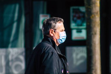 Fransa 'yı 20 Şubat 2021' de Reims sokaklarında yürüyen ve Fransa 'yı etkileyen salgın sırasında kendilerini koronavirüsten korumak için maske takan kimliği belirsiz bir yaya.