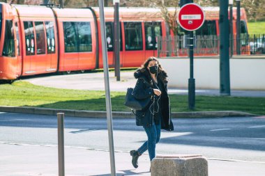 Fransa 'yı 18 Mart 2021' de Reims sokaklarında yürüyen ve Fransa 'yı etkileyen salgın sırasında kendilerini koronavirüsten korumak için maske takan bir yaya.