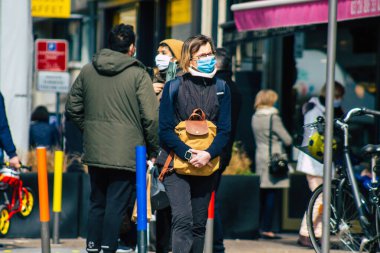 Paris Fransa 20 Mart 2021 'de Paris sokaklarında yürüyen ve nüfusu zapt etmek için koronavirüsten kendini korumak için maske takan bir yayaydı.