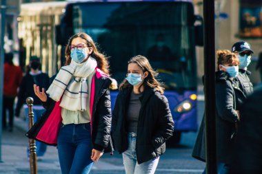 Paris Fransa 20 Mart 2021 'de Paris sokaklarında yürüyen ve nüfusu zapt etmek için koronavirüsten kendini korumak için maske takan bir yayaydı.