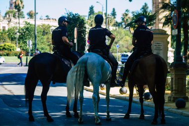 Sevilla İspanya 23 Temmuz 2021. Coronavirus salgını sırasında Seville caddesinde at süren polis memuru İspanya 'ya saldırdı. Sokakta maske takmak zorunlu değil ama çoğu insan bunu takıyor.