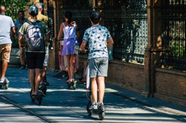 Seville İspanya 11 Ağustos 2021 Seville sokaklarında elektrikli scooterla dolaşan insanlar, küçük bir iç yanmalı motorlar ve merkezde bir güverte ile çalışıyorlar.